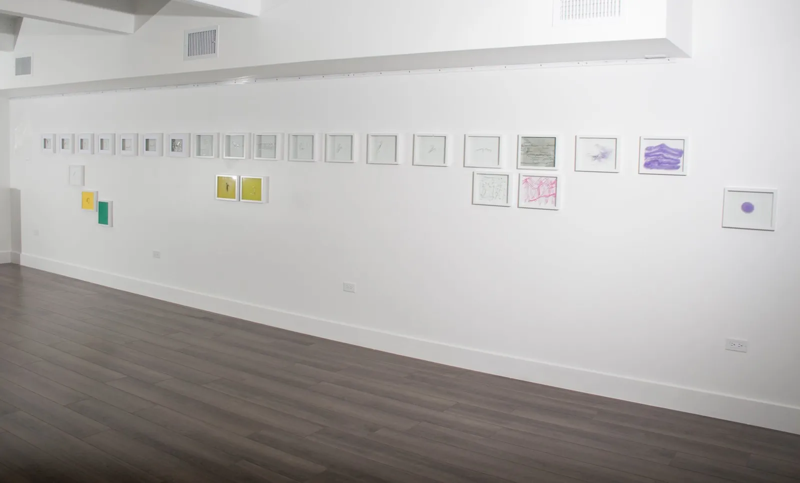 Long wall of small framed works in a horizontal line